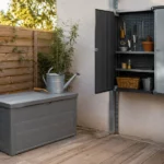 Coffre de jardin en résine sur une terrasse à côté d'une armoire de rangement murale, avec surfaces en résine, métal galvanisé et bois traité, dans un jardin résidentiel bien organisé.