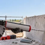 Artisan injectant une résine de scellement chimique dans un mur en béton avant la pose d’une tige filetée.